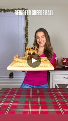 a woman holding up a tray with food on it and the words reindeer cheese ball in front of her