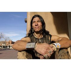 a man with long hair sitting on the side of a building