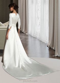 a woman in a white wedding dress looking at herself in the mirror with her hand on her hip