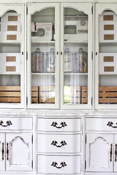 a white china cabinet with glass doors and drawers