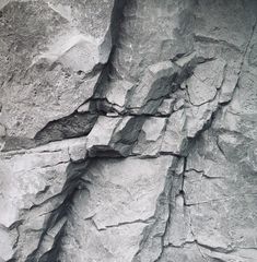 a black and white photo of rocks with cracks in the rock face that looks like they have been cut off