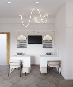 an empty salon with two white tables and chairs in front of the counter, lights hanging from the ceiling