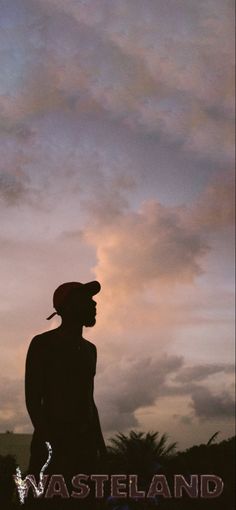 the silhouette of a person wearing a hat and standing in front of a cloudy sky