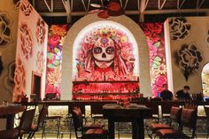 a mexican themed restaurant is decorated with sugar skulls and colorful florals on the walls