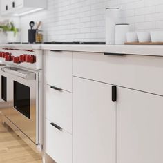 a kitchen with white cabinets and stainless steel appliances, along with wooden flooring that matches the countertops