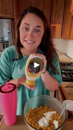 a woman holding a blender in her hand next to a bowl of cereal