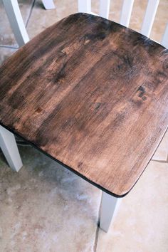 a wooden chair sitting on top of a tiled floor next to a white table and chairs