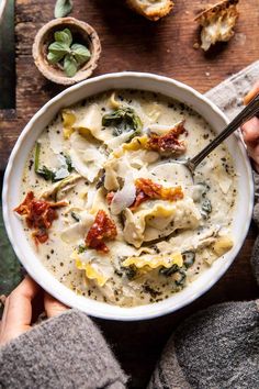 someone holding a bowl of pasta and spinach soup