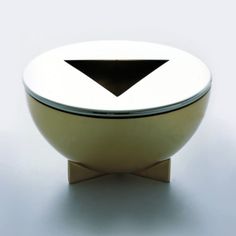 a white bowl sitting on top of a wooden stand with a black triangle in the center