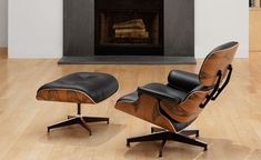 an eames chair and ottoman in front of a fireplace