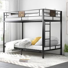 a black metal bunk bed with white sheets and yellow pillows on the bottom, next to a window