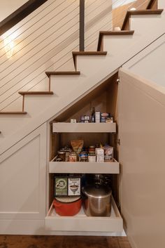 an under the stairs storage area with food and condiments on shelves underneath it