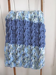 a blue and white crocheted blanket hanging from a wooden chair next to a door