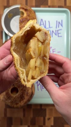 a person is holding an apple pie in their left hand, with the inside half eaten