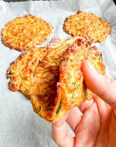 someone is holding up some food on a piece of wax paper with four other items in the background