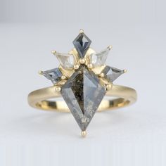 a yellow gold ring with two different colored diamonds on it's sides and an arrow shaped diamond in the middle