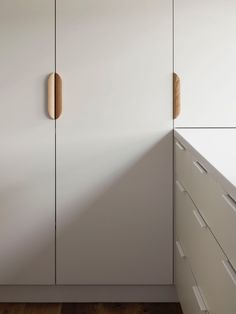 a white cabinet with wooden handles in a room