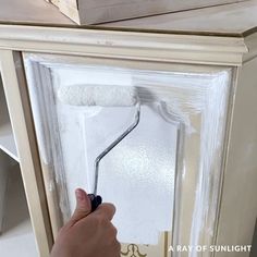 someone is painting the side of a cabinet with white paint