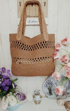 a brown bag sitting on top of a table next to flowers and other things in front of it