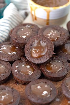 chocolate cookies with caramel filling on a wooden board next to a bowl of peanut butter