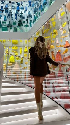 a woman is walking down some stairs in front of many glass items on the wall