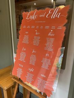 an orange and white wedding seating chart on a easel