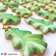 decorated cookies arranged in the shape of christmas trees on a white table with gold stars