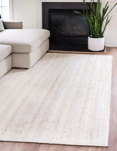 a living room with a white couch and a rug on the floor in front of a fireplace