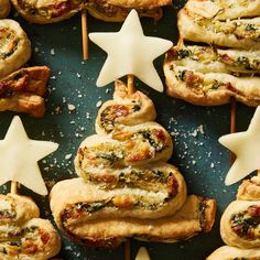 small pastries with star shaped toppings are arranged on a blue surface next to white stars