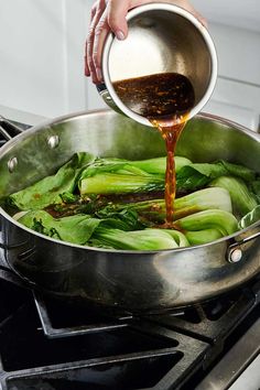 someone is pouring sauce on some vegetables in a pan