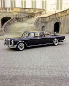 an old black car parked in front of some stairs