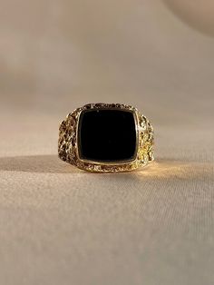 Vintage 9k yellow gold onyx signet ring from the United Kingdom, featuring beautiful hammered textured shoulders. Excellent vintage condition Size: 9.5 Weight: 8.2 grams Band: 15.5 mm (front), 2.8 mm (back) Onyx: 11.7 mm x 12.8 mm Hallmarks: 9 for 9k Please note, vintage and antique jewelry may come with imperfections commensurate of their age. To see more photos and videos of this piece, visit our Instagram: www.instagram.com/23carat PLEASE READ ALL POLICIES regarding shipping, returns, tax, et Elegant Gold Signet Ring With Black Enamel, Heirloom Gold Signet Ring With Black Enamel, Gold Heirloom Signet Ring With Black Enamel, Luxury Black Signet Ring Tarnish Resistant, Vintage Tarnish Resistant Signet Ring For Formal Occasions, Timeless Gold Signet Ring With Black Enamel, Formal Gold Onyx Signet Ring, Formal Gold Signet Ring With Onyx, Gold Onyx Signet Ring For Formal Occasions