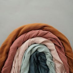 several different colored scarves stacked together on top of each other, with one folded in the middle