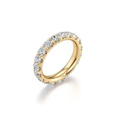 a yellow gold wedding band with round cut diamonds on the top and bottom, set against a white background