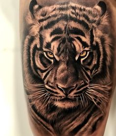 a close up of a tiger's face on a man's leg with black and grey ink