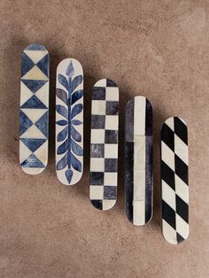 four skateboards are lined up in a row on the floor, one is painted with blue and white designs