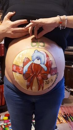 a pregnant woman is holding her belly painted with an image of a teddy bear on it