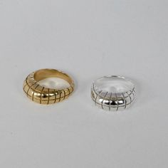 two gold and silver rings sitting next to each other on a white surface, one with an open ring in the middle