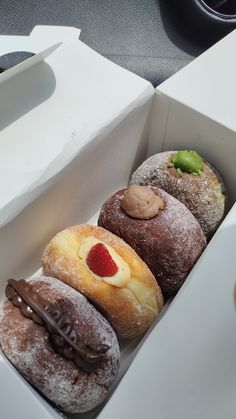 four pastries in a white box on a table