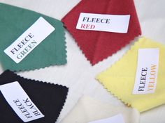 four pieces of cloth with labels on them that read fleece green, red, yellow and black