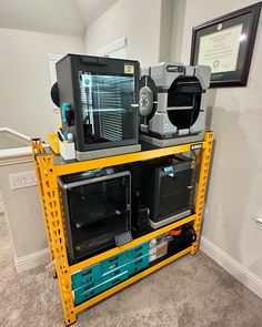 two microwaves are stacked on top of each other in a storage area with yellow shelving