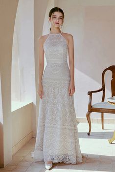 a woman in a white dress standing next to a chair