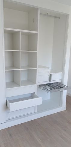 an empty room with white shelves and drawers on the wall, in front of a stove top oven