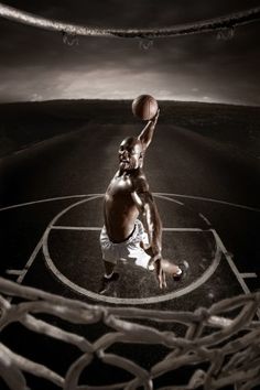 a man dunking a basketball into the hoop in an empty basketball court at night