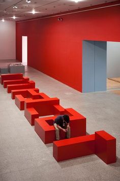 a man kneeling down on top of red steps in an empty room with white walls