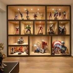 a display case filled with lots of action figures on wooden shelves in front of a wall