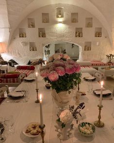 a dining room table is set with flowers and candles in vases on the tables