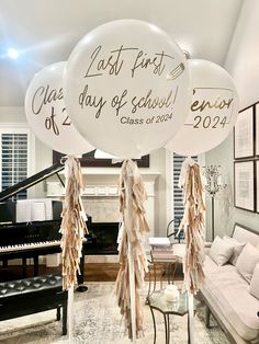 balloons with names and date written on them hanging from the ceiling in a living room