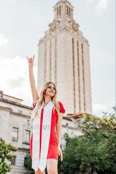 a woman is standing in front of a tall building with her hand up to the sky