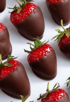 chocolate covered strawberries are arranged on a white surface